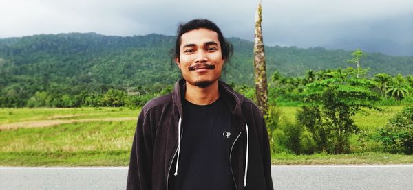 Portrait of young man standing against trees