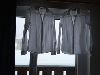 Shirts hanging against glass window at home