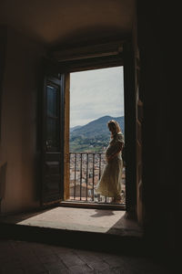 Rear view of woman looking through window