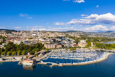 High angle view of townscape by sea against blue sky