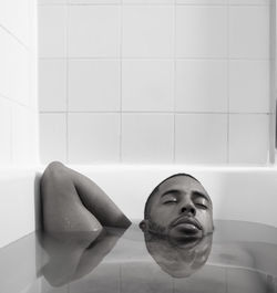 Man with eyes closed relaxing in bathtub