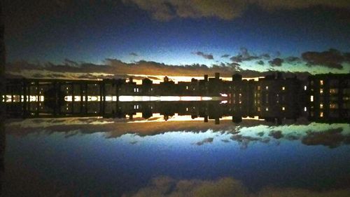 Scenic view of lake by buildings against sky at dusk