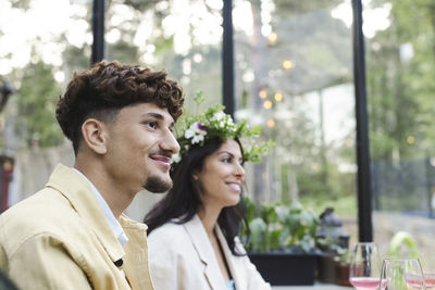 Smiling man sitting by woman wearing tiara at dinner party