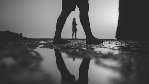 Low section of man walking by woman at beach