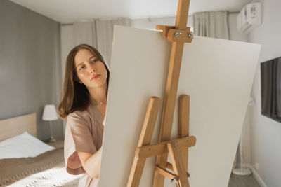 Portrait of young woman sitting on bed at home