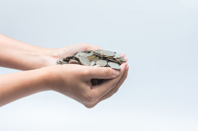 Close-up of hand holding ring over white background