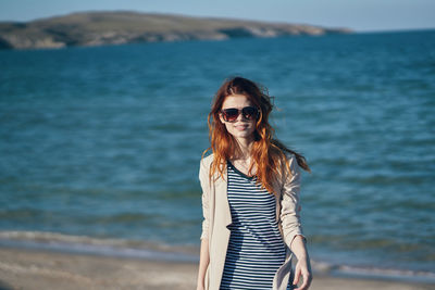 Young woman wearing sunglasses standing on beach