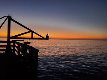 Silhouette pier over sea against sky during sunset