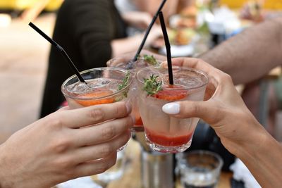 Cropped hands of friends toasting drinks