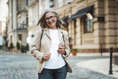 Portrait of young woman standing in city