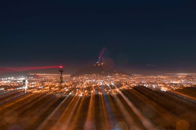 Illuminated cityscape against sky at night