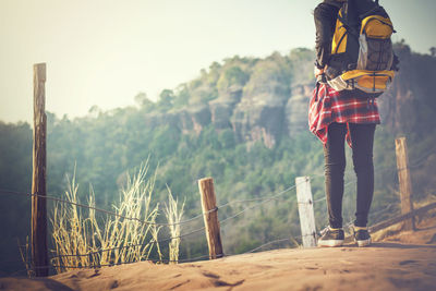 Rear view of man standing on railing against mountain