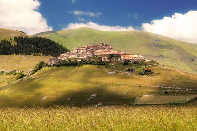 Houses on hill at castelluccio against sky