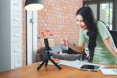 Young woman using phone while standing on table