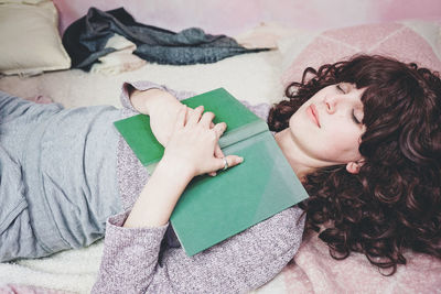 Woman reading book on bed at home