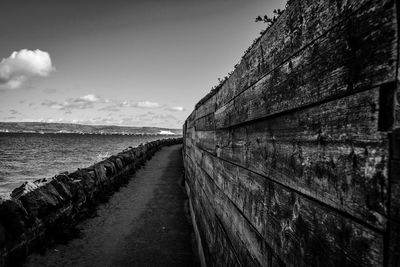 Footpath by sea against sky