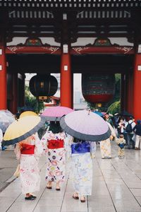 Women with umbrella walking against temple