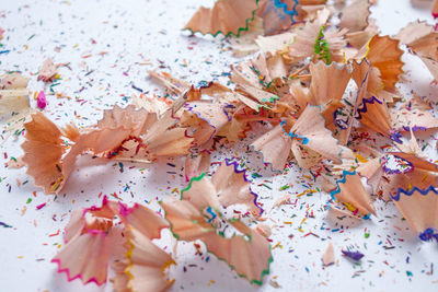 High angle view of colored pencils shavings on white background