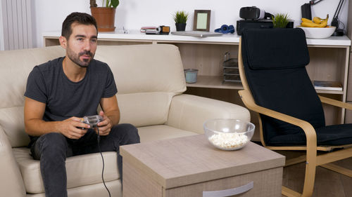 Portrait of young man using mobile phone while sitting on table