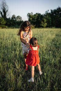 Two girls in dresses playing with each other the evening field