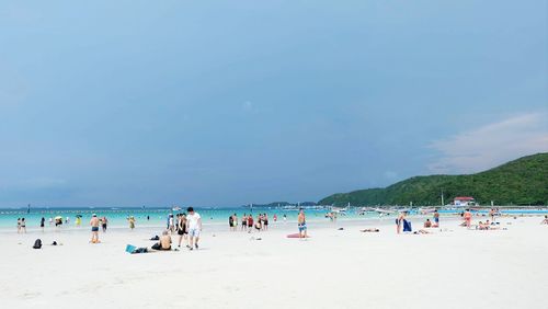 People at beach against blue sky