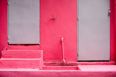 Close-up of closed steel door of pink walled building