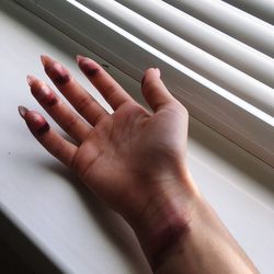 Cropped hand with make-up by window