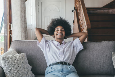 Portrait of young woman sitting on sofa at home