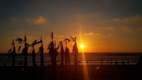 Silhouette people on beach against sky during sunset