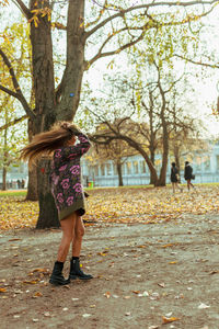 Woman tossing hair while standing at park during autumn