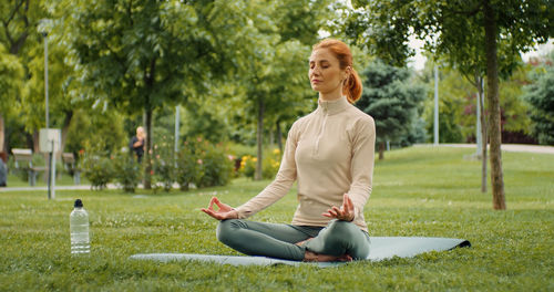 Young woman sitting on yoga mat in lotus position. 