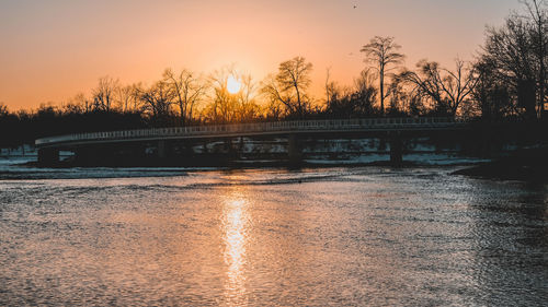 Bridge over river against sky during sunset