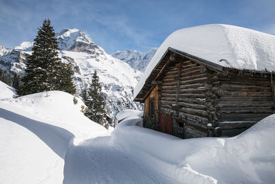 Snow covered houses and mountains against sky