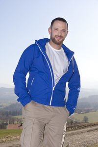 Portrait of man with hands on pockets while standing against sky