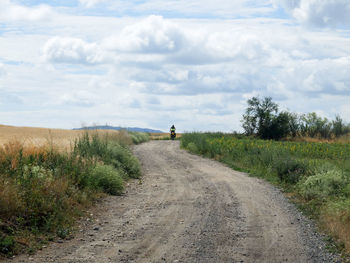 Road amidst field against sky