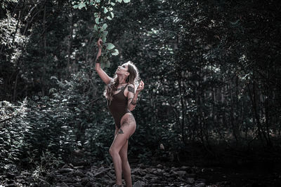 Full length of woman with arms raised in forest
