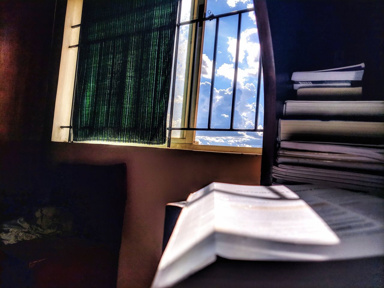 STACK OF BOOKS ON TABLE BY WINDOW