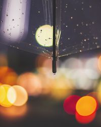 Close-up of raindrops on illuminated lights at night