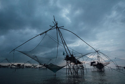 Fishing net in sea against sky at dusk