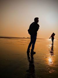 Silhouette man standing on beach against sky during sunset