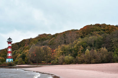 Lighthouse by trees against sky