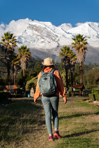 Tourist walks through the town named yungay with the snow-capped huascaran in the background.