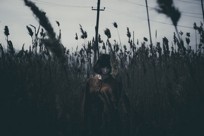 Woman sitting on field against sky