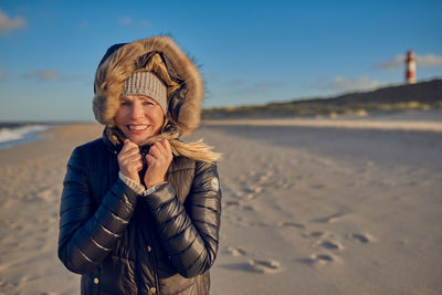 Portrait of smiling young woman standing on beach