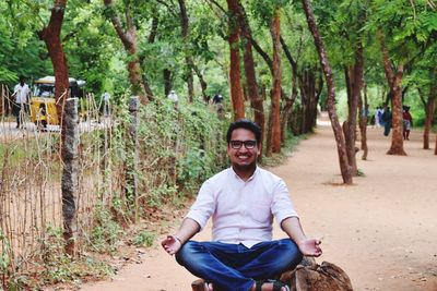 Portrait of man sitting on tree trunk