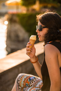 Midsection of woman holding glass while sitting outdoors