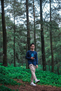 Full length of young man standing at forest