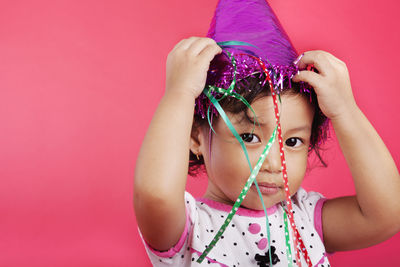 Portrait of cute girl wearing party hat against red background