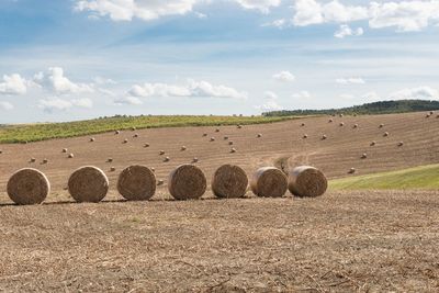 Hay bales on field against sky