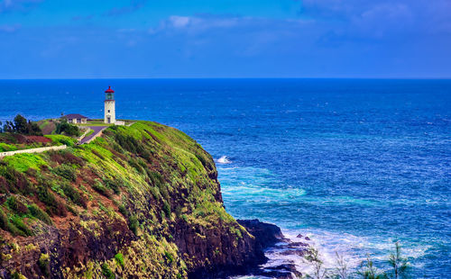 Lighthouse by sea against sky